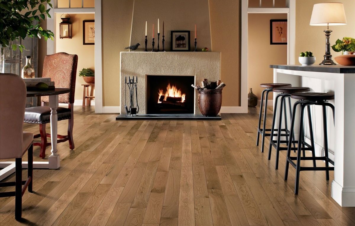 Kitchen area with island on one side, dining table on the other and a fireplace between with solid hardwood flooring