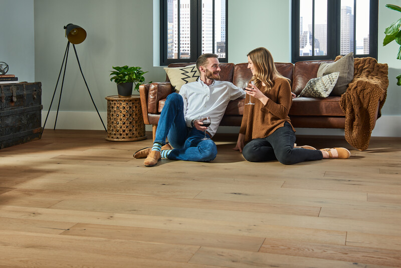 Couple seated on the floor talking; hardwood floor care