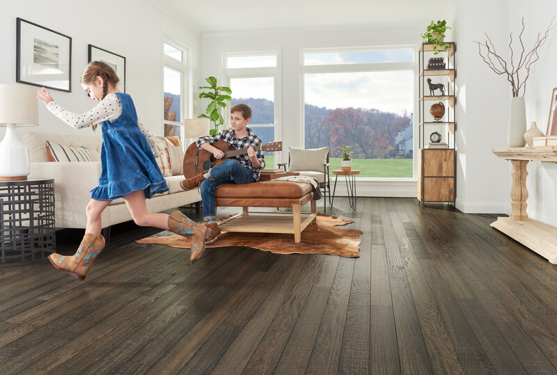 Living room space with teens playing showing a hardwood floor made in the USA